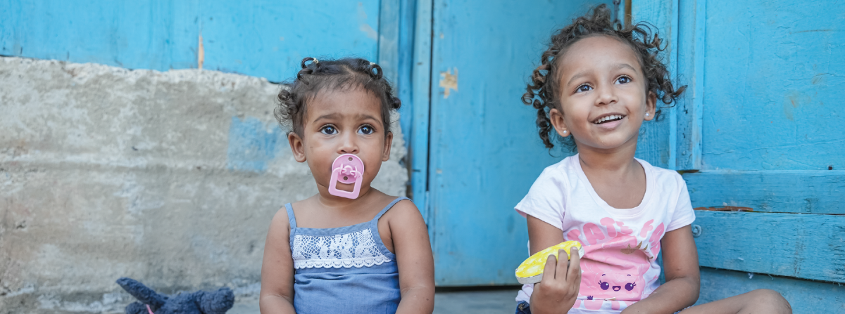 Dos niñas sentadas en el piso junto a sus juguetes